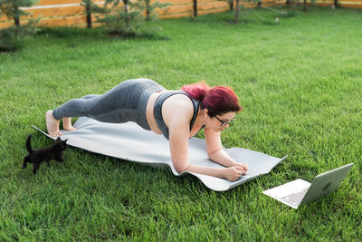 Side view of woman using laptop while sitting on grassy field