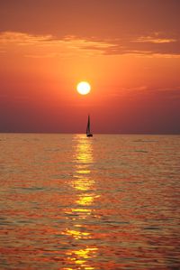 Sunset over lake michigan with a sailboat against an orange sky