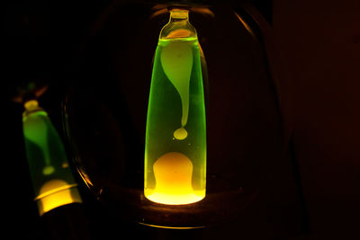 Close-up of illuminated glass bottle against black background