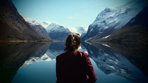 Man standing on mountain by lake against sky