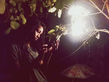 Young woman holding illuminated tree