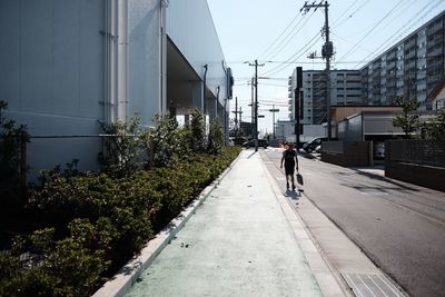 Rear view of man walking on road in city