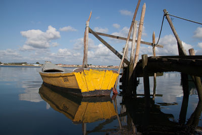 Sailboats moored in sea against sky