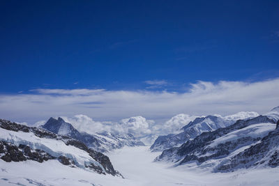 Scenic view of snowcapped mountains against blue sky