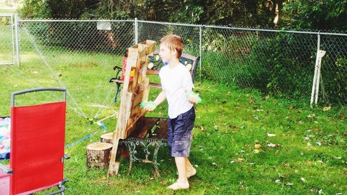 Full length of boy standing by fence in yard