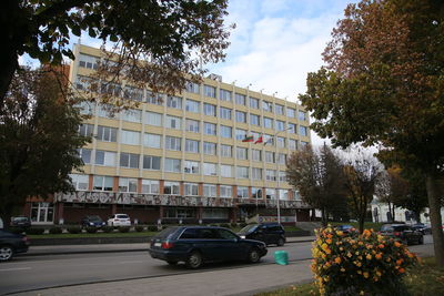 Cars on road by buildings against sky