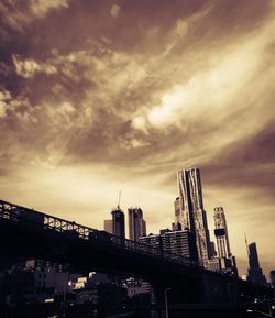 Low angle view of skyscrapers against cloudy sky