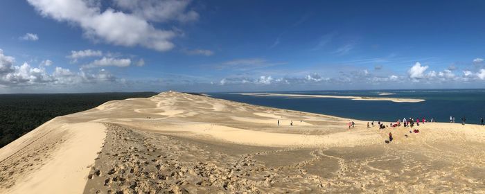 Panoramic view of people on beach against sky