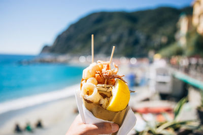 Cropped hand holding food at beach