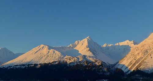 Scenic view of snowcapped mountains against clear blue sky