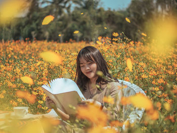 Portrait of woman holding flowers on field