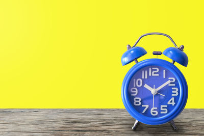 Close-up of clock on table against wall