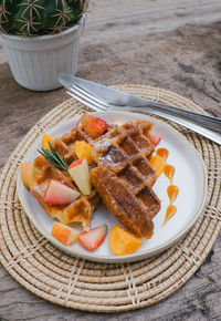 Waffles with blueberries and strawberry for breakfast on wooden background.