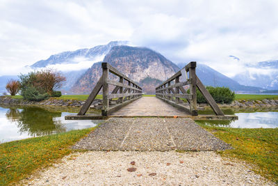 Footbridge over lake against cloudy sky