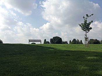 Scenic view of grassy field against cloudy sky