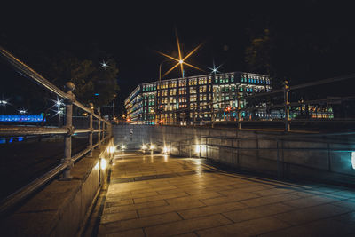 Illuminated bridge over street amidst buildings in city at night