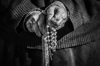 Close-up of midsection woman holding rosary beads