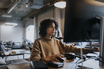 Female programmer concentrating while working on computer at desk in office