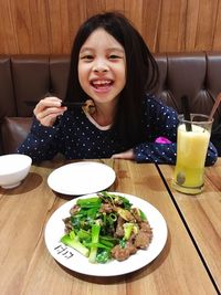 Close-up of a smiling young woman eating food at home