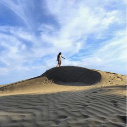 Man on sand dune in desert against sky