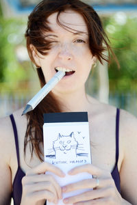 Portrait of cheerful woman holding cat drawing on notepad