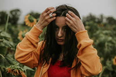 Young woman standing amidst sunflowers on field