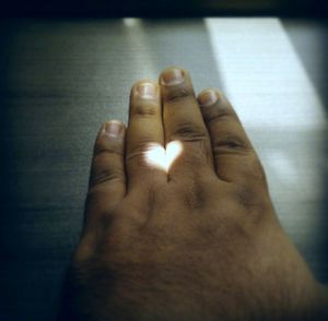 High angle view of sunlight forming heart shape on hand