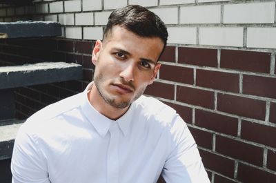 Portrait of young man standing against wall