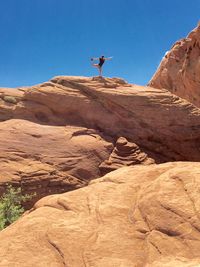 Man on rock against clear sky