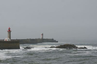 Lighthouse by sea against clear sky