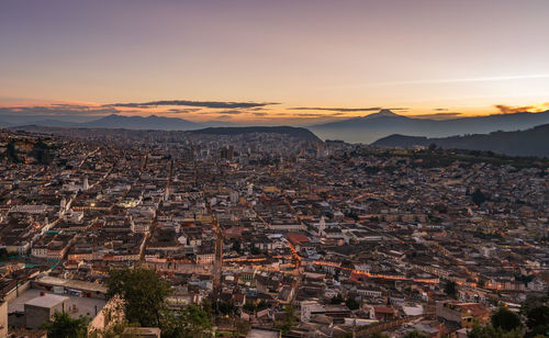 Aerial view of illuminated cityscape against sky at sunset