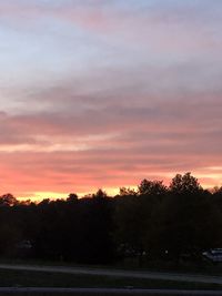 Silhouette trees on field against romantic sky at sunset