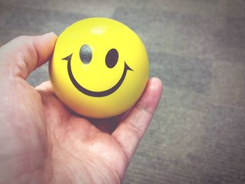 Cropped hand holding smiley face stress ball