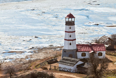 Lighthouse by sea against sky