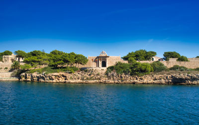 Building by sea against clear blue sky