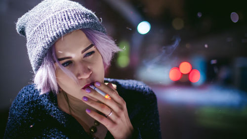 Close-up of young woman smoking cigarette at night