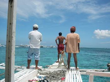 Rear view of people standing by sea in cebu against sky