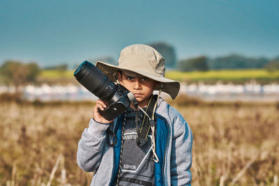 Portrait of man wearing hat standing on field