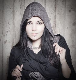 Portrait of beautiful young woman standing against wall