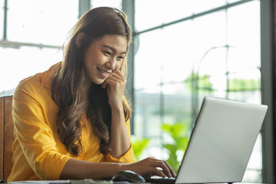 Smiling businesswoman using laptop on desk in office