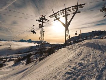 Electricity pylon on snowcapped mountain against sky