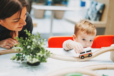 Baby boy by mother playing with toy car