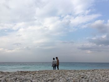 Rear view of men on beach against sky