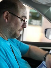 Side view of man looking down while sitting in car