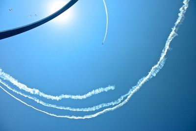 Low angle view of vapor trails against blue sky