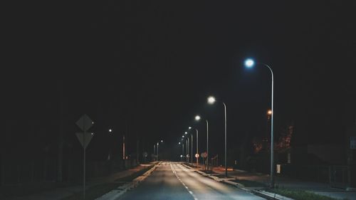 Illuminated street lights on road at night