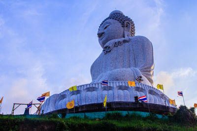 Low angle view of buddha statue amidst flags against sky