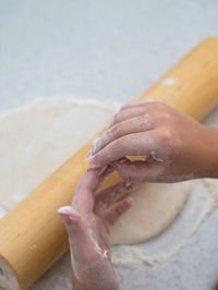 Cropped hand of girl rolling dough