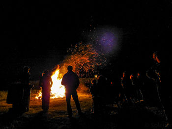 People standing by bonfire at night