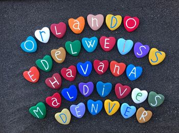 Directly above shot of colorful heart shape decorations with text on sand